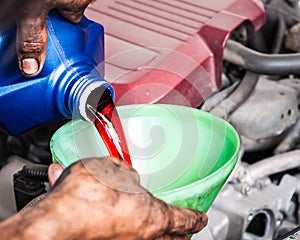 Hand pouring transmission fluid through funnel photo