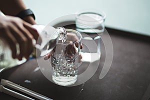 Hand pouring water into a glass bottle