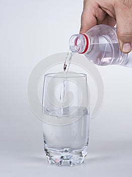 Hand pouring water to glass from plastic bottle