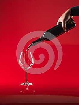 Hand pouring wine in glass from bottle photo