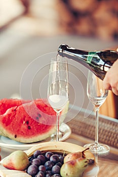 Hand pours champagne into tall glasses