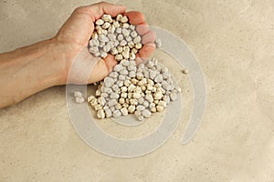 Hand pours dried chickpeas on the craft paper, good source of vegetable protein, copy space