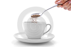 Hand pours instant coffee from a spoon in a coffee cup