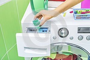 Hand pours liquid powder into the washing machine.