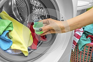 Hand pours liquid powder into the washing machine.