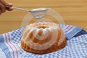 Hand powdering a traditional bundt cake with sugar photo