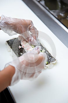 hand prepares sushi roll