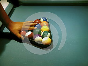 Hand preparing pool balls in triangle rack on the billiard table