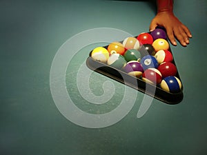 Hand preparing pool balls in triangle rack on the billiard table with copy space