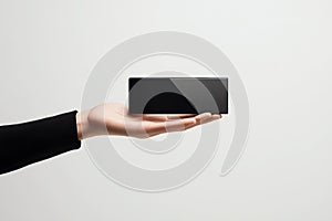 Hand presenting a black rectangular electronic device isolated on white background
