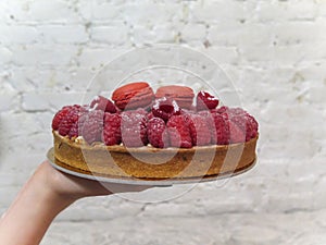 Hand Presenting a Raspberry Tart with Macaroons