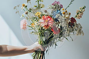 Hand presents colorful assortment of summer flowers, showcasing freshness and natural beauty