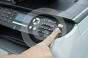 Hand press button on panel of printer scanner or laser copy machine in office
