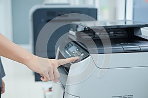 Hand press button on panel of printer scanner or laser copy machine in office