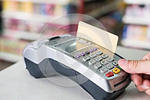 Hand press with swiping credit card on payment terminal in store