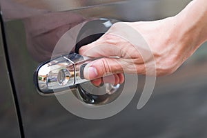 Hand press unlock button alarm system on black car .