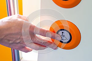 Hand presses a button for disabled people on the train