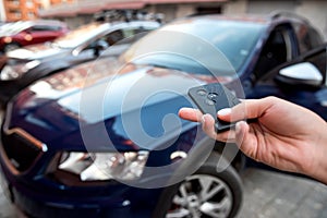 hand presses the car alarm control panel in front of his own new car.