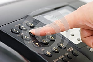 The hand presses the fax button