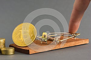Hand presses  mousetrap with the coin bitcoin.