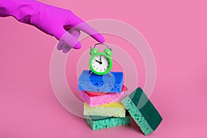 hand pressing alarm clock with sponges on isolated pink background signaling it is time to clean up cleaning concept.