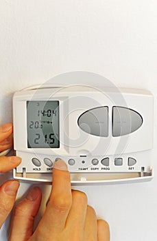 Hand pressing button on digital thermostat