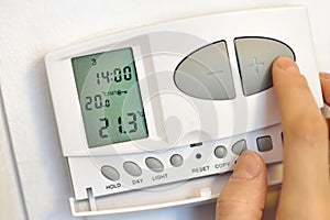 Hand pressing button on digital thermostat