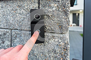 Hand pressing button of video intercom mounted on the stone wall photo
