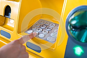 Hand pressing the code from the ATM focuses on the numbers and the finger area