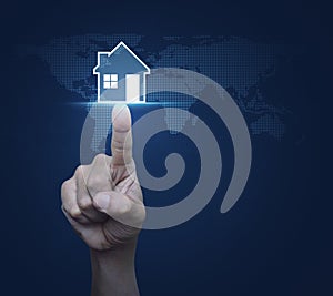 Hand pressing house icon with copy space over digital world map