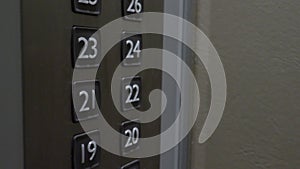 Hand pressing lift button up to high floor of office building or hotel condominium