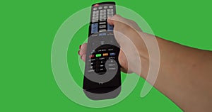 Hand pressing remote control button over green background