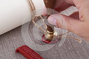 Hand pressing seal stamp to the rope of document with wax seal