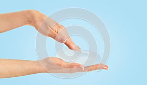 Hand pressing soft breast implant in hand on blue background, copy space.