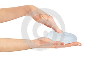 Hand pressing soft breast implant in hand on white background with clipping path.