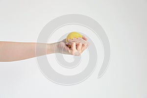 Hand pressing yellow squishy ball for exercise muscle or for feeling relax from stress; concept of health care and medical