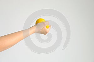 Hand pressing yellow squishy ball for exercise muscle or for feeling relax from stress; concept of health care and medical