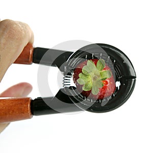 Hand pressuring a strawberry with nutcracker