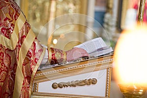 Hand of priest on the desk reading Bible in the Orthodox church