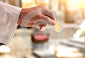 Hand of a priest giving a consecrated host for communion