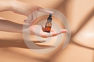 Hand, product and serum with a woman on a beige background to promote an antiaging treatment. Skincare, beauty and