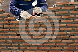 hand of professional construction worker laying bricks In wall construction