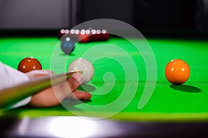 Hand of professional snooker player closeup aiming shot white ball on table