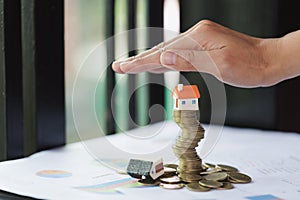 Hand protection, house model on top of stack of money as growth