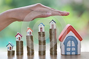 Hand protection, house model on top of stack of money as growth