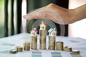 Hand protection, house model on top of stack of money as growth