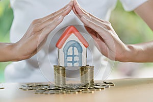 Hand protection, house model on top of stack of money as growth