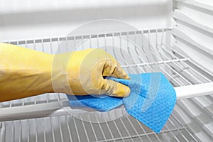 Hand with protective glove cleaning refrigerator