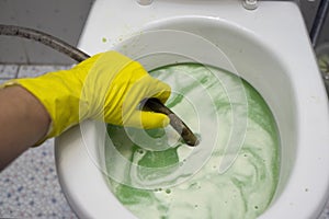 Hand fixing clogged toilet photo