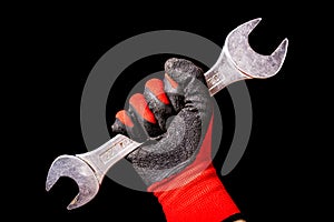 Hand with protective gloves holding wrench tool isolated on black background